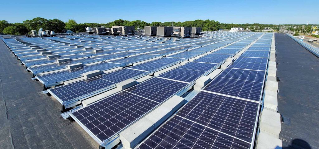 Solar panel installation on a commercial roof at an Audi dealership in Cape Cod, MA, showcasing numerous solar panels aligned for optimal sunlight exposure.