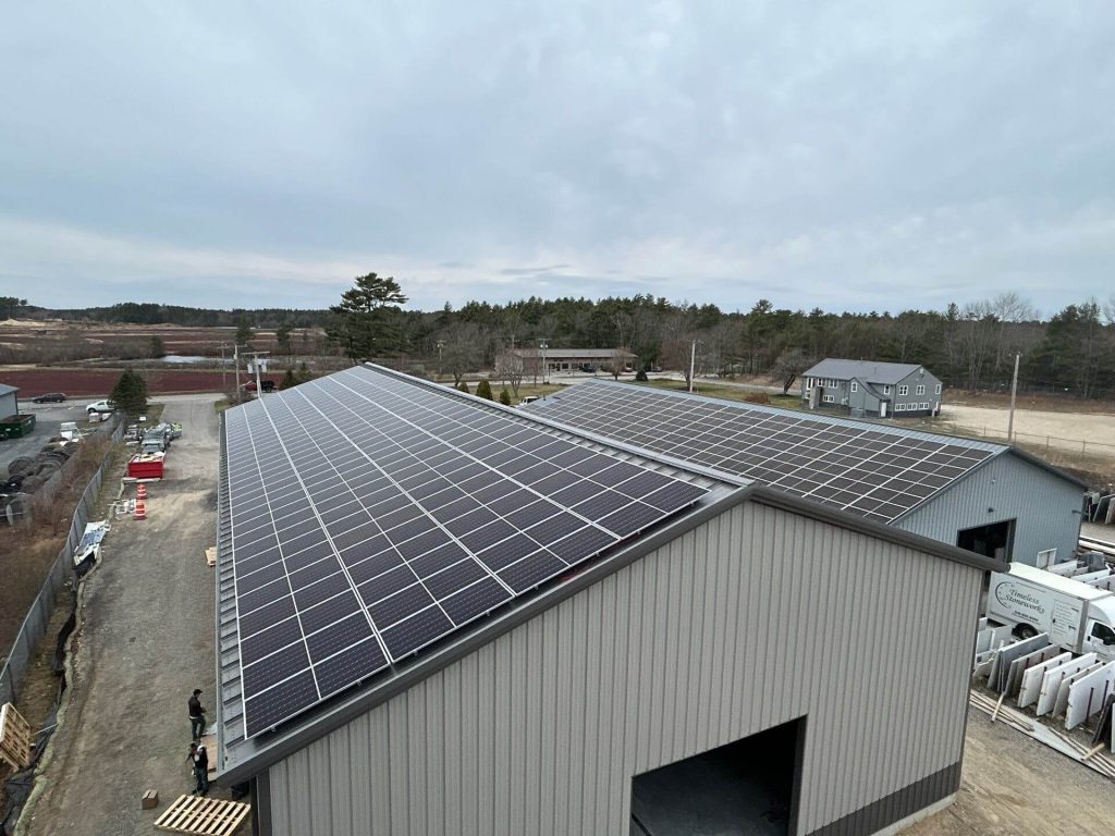 Solar panels installed on commercial buildings with a cloudy sky backdrop, showcasing renewable energy solutions for local businesses by BD Electrical Services.