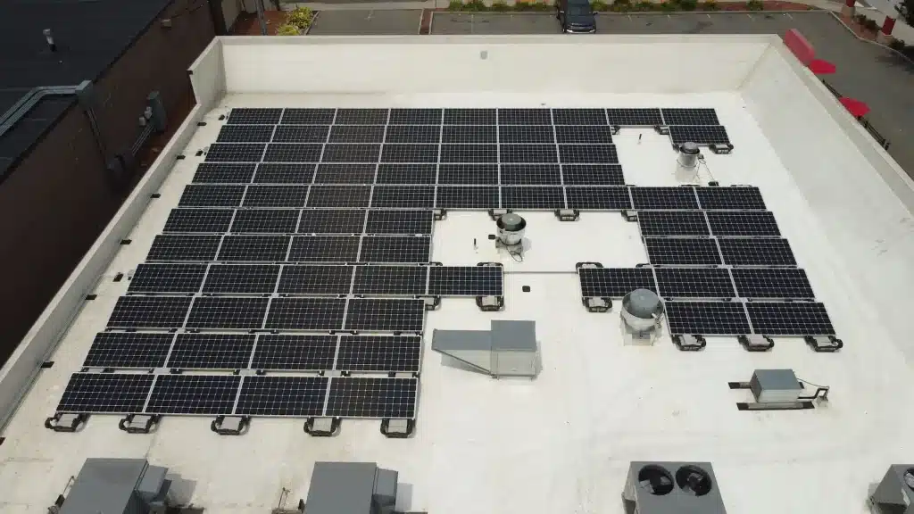 Solar panel installation on the roof of a small restaurant, showcasing a grid of solar panels and HVAC units, emphasizing commercial solar power solutions for local businesses.