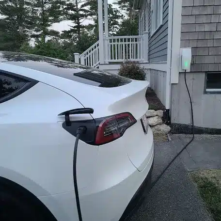 Tesla charging from a wall-mounted home charger at a Plymouth residence